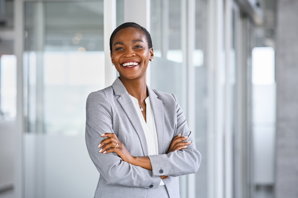 The same African American woman stands smiling in the office - she has successfully given her coworkers the benefits of outsourced cfo services