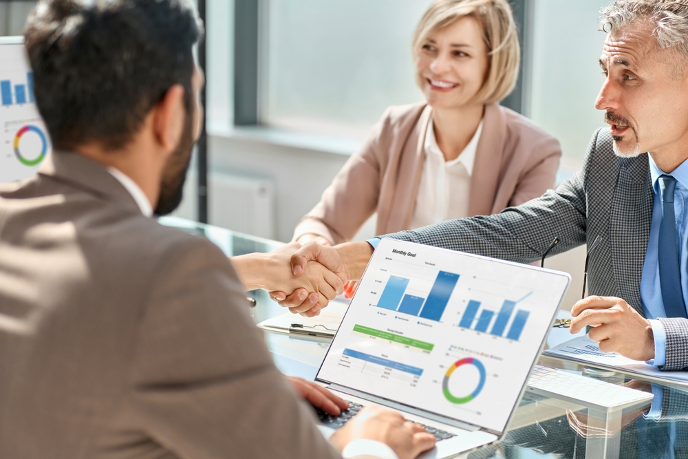 a business owner and outsourced CFO shaking hands after a presentation of data