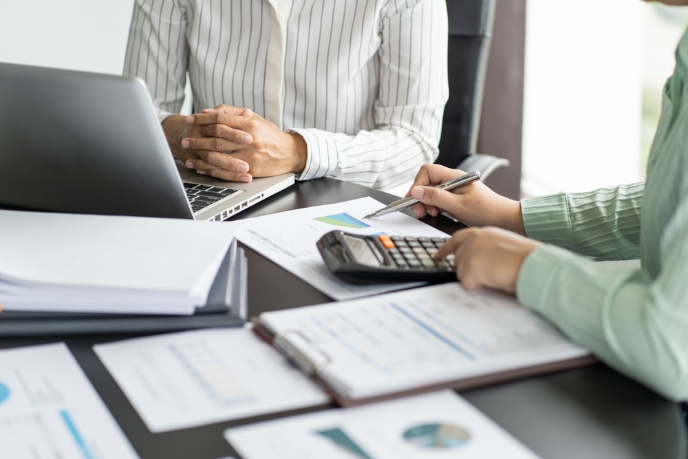 two men in button ups with paper and a calculator conducting a sales tax audit