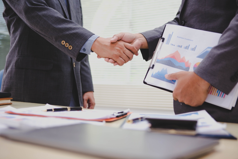 Two accountatnts shaking hands after finalizing the M&A structure for a major business merger