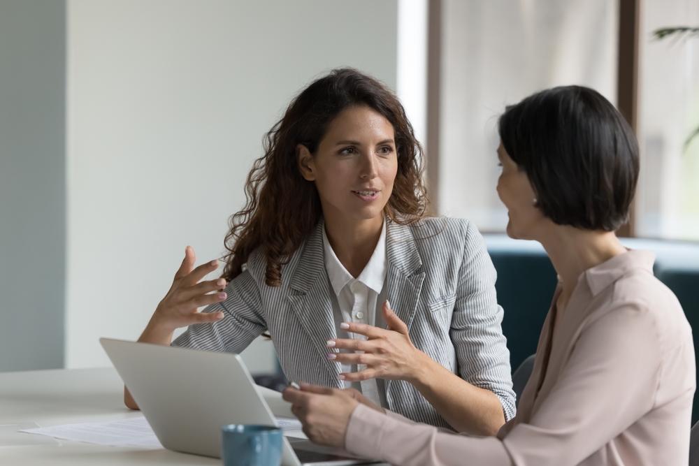 two woman in business casual sitting discussing the tax implications of selling a business