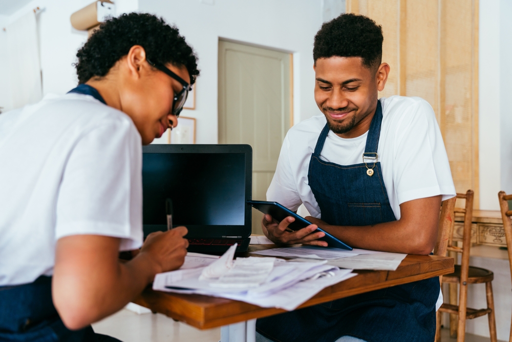 Bakery, portrait of hispanic black man and woman in cafe calculating costs and taxes - Small business owners tracking income and expenses, checking balance and doing financial plan