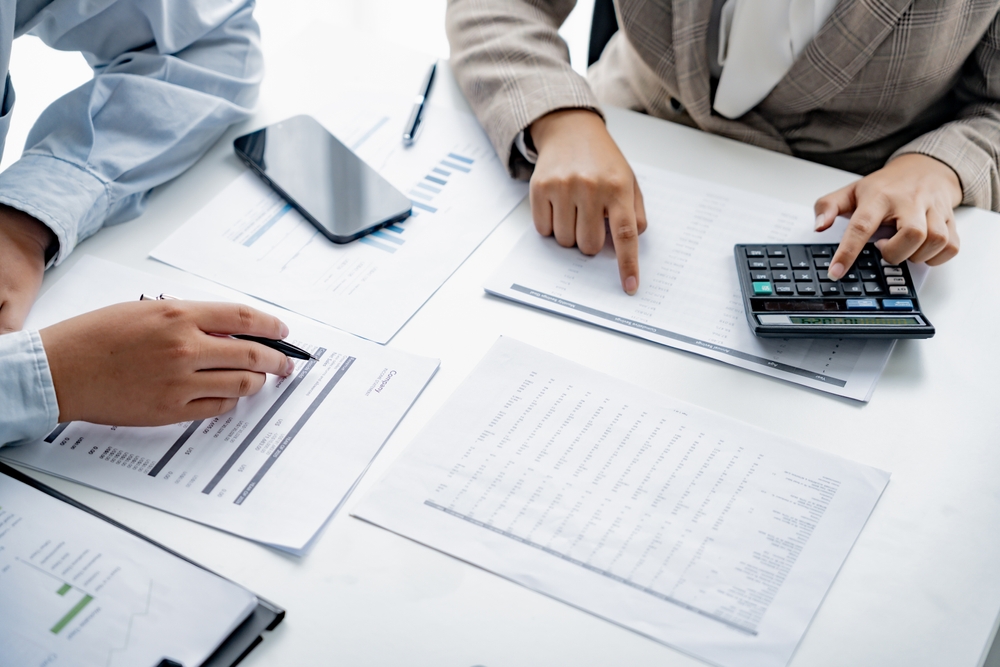 financial officer checking calculator with paper documents to review business annual report in office