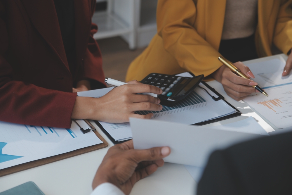 Financial analysts analyze business financial reports on a digital tablet planning investment project during a discussion at a meeting of corporate showing the results of their successful teamwork.