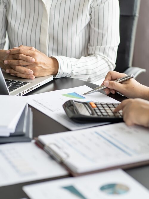 two men in button ups with paper and a calculator conducting a sales tax audit
